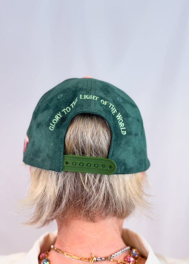 Woman shown from back wearing dark green suede trucker hat with &