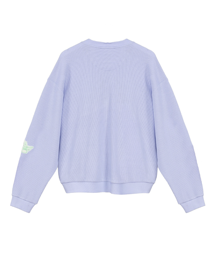 A light lavender ribbed knit crewneck sweatshirt shown from the back, featuring a small light green wing graphic on the left sleeve, set against a plain white background.