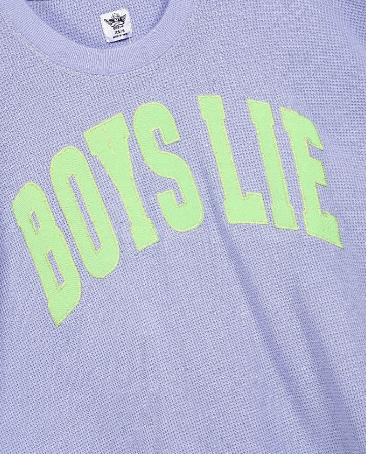 A close-up of a light lavender waffle-knit t-shirt featuring the phrase &