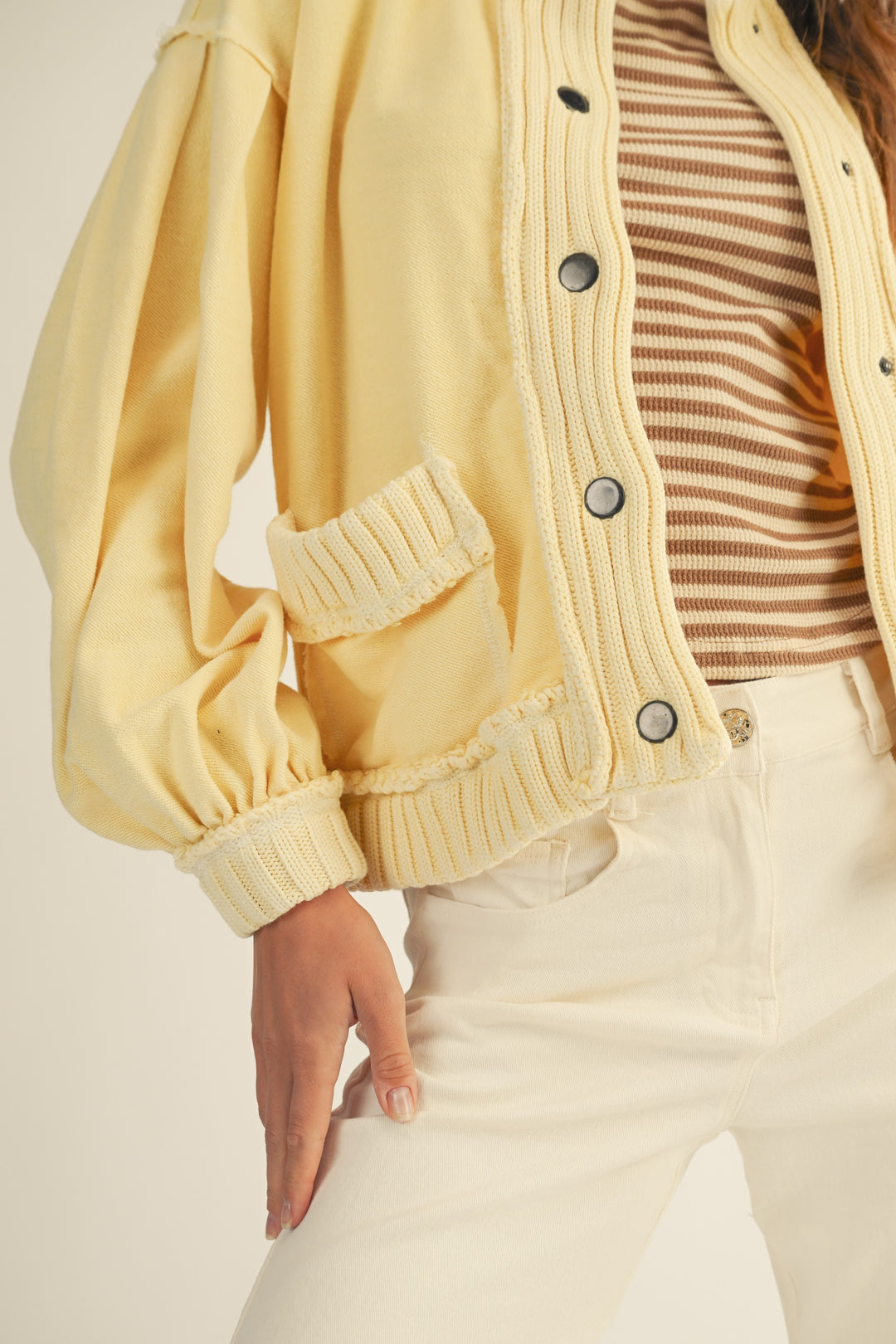 Person wearing a yellow cardigan over a striped shirt with a neutral background