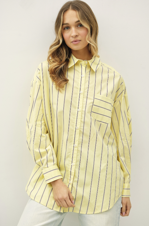 Woman wearing yellow stripe button up shirt and jeans on plain background