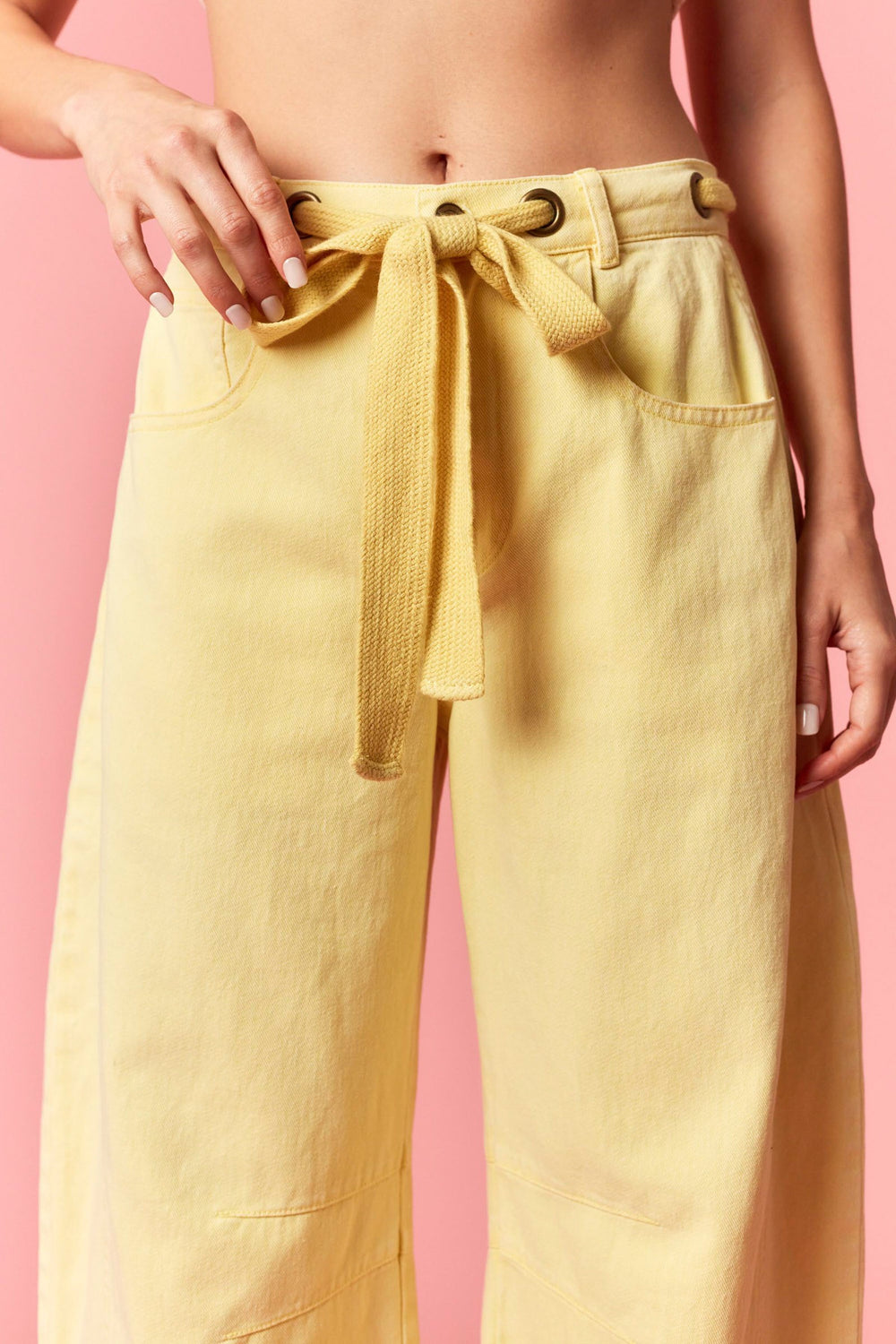 Yellow pants with a tie waist on a pink background