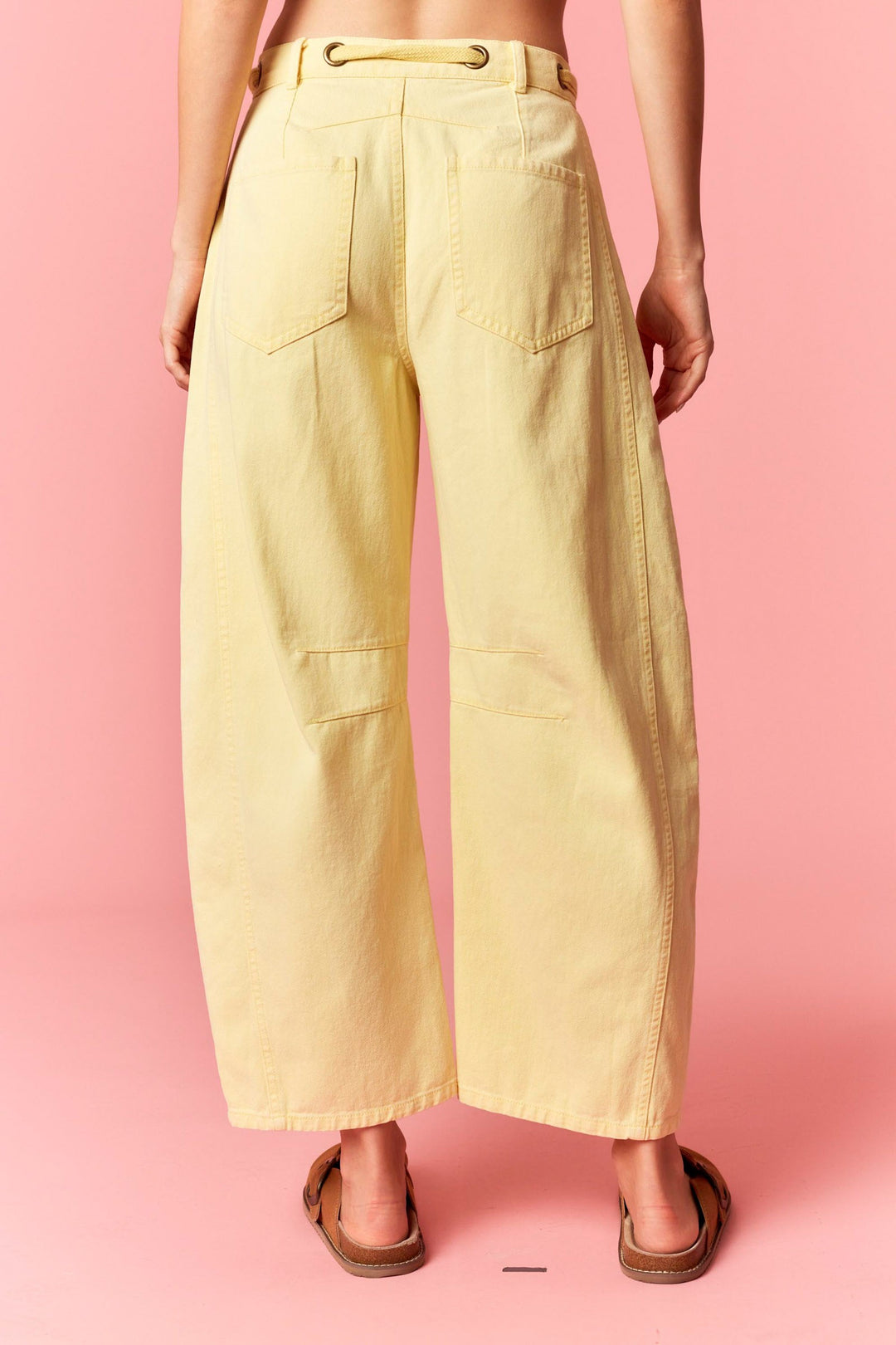 Person wearing light yellow pants on a pink background