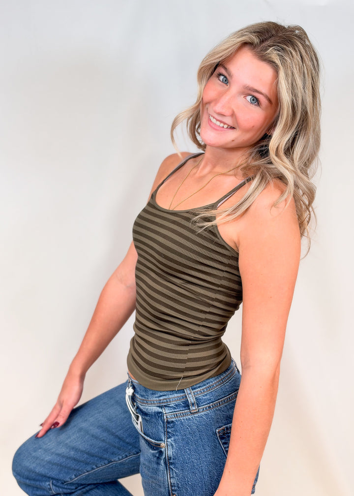 Woman wearing green stripe tank and jeans on plain background