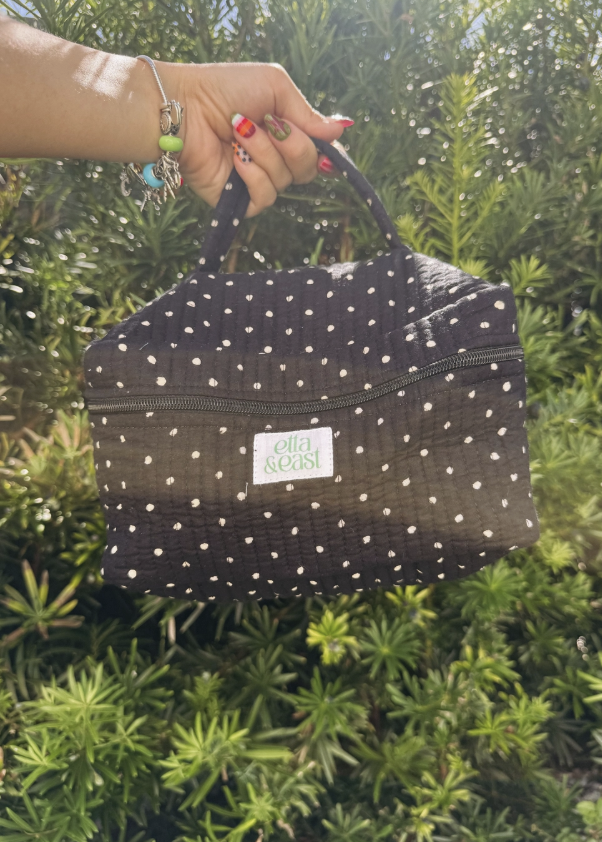 Black polka dot makeup bag in womans hand outdoors