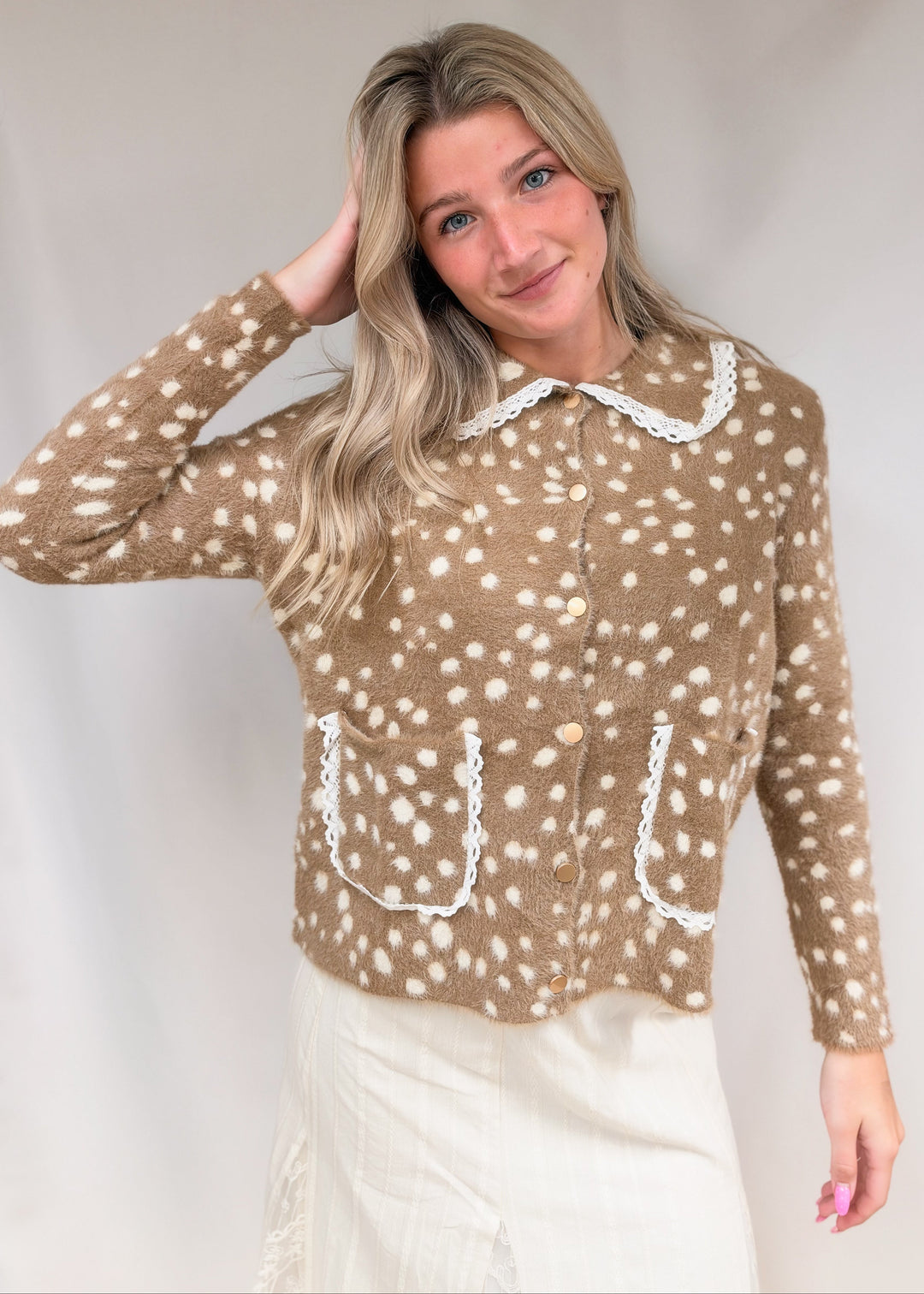 Woman wearing fawn print fuzzy cardigan with lace details on plain background