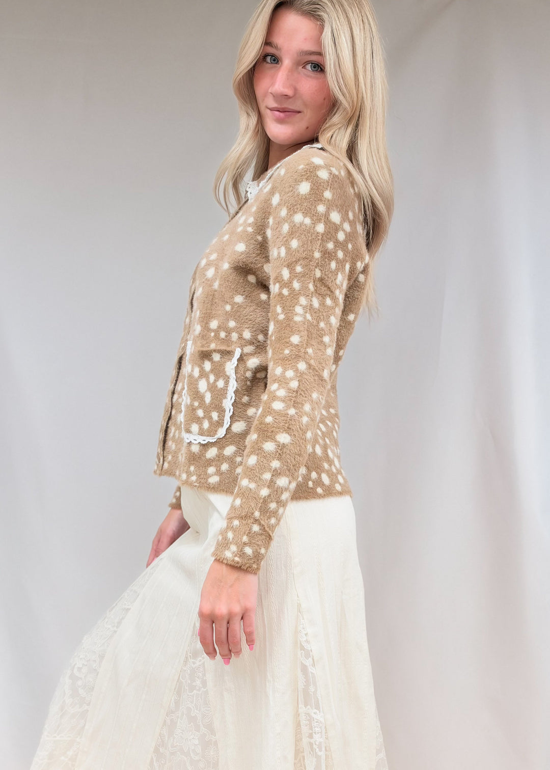 Woman shown from side view wearing fawn print fuzzy cardigan with lace detail maxi skirt on plain background