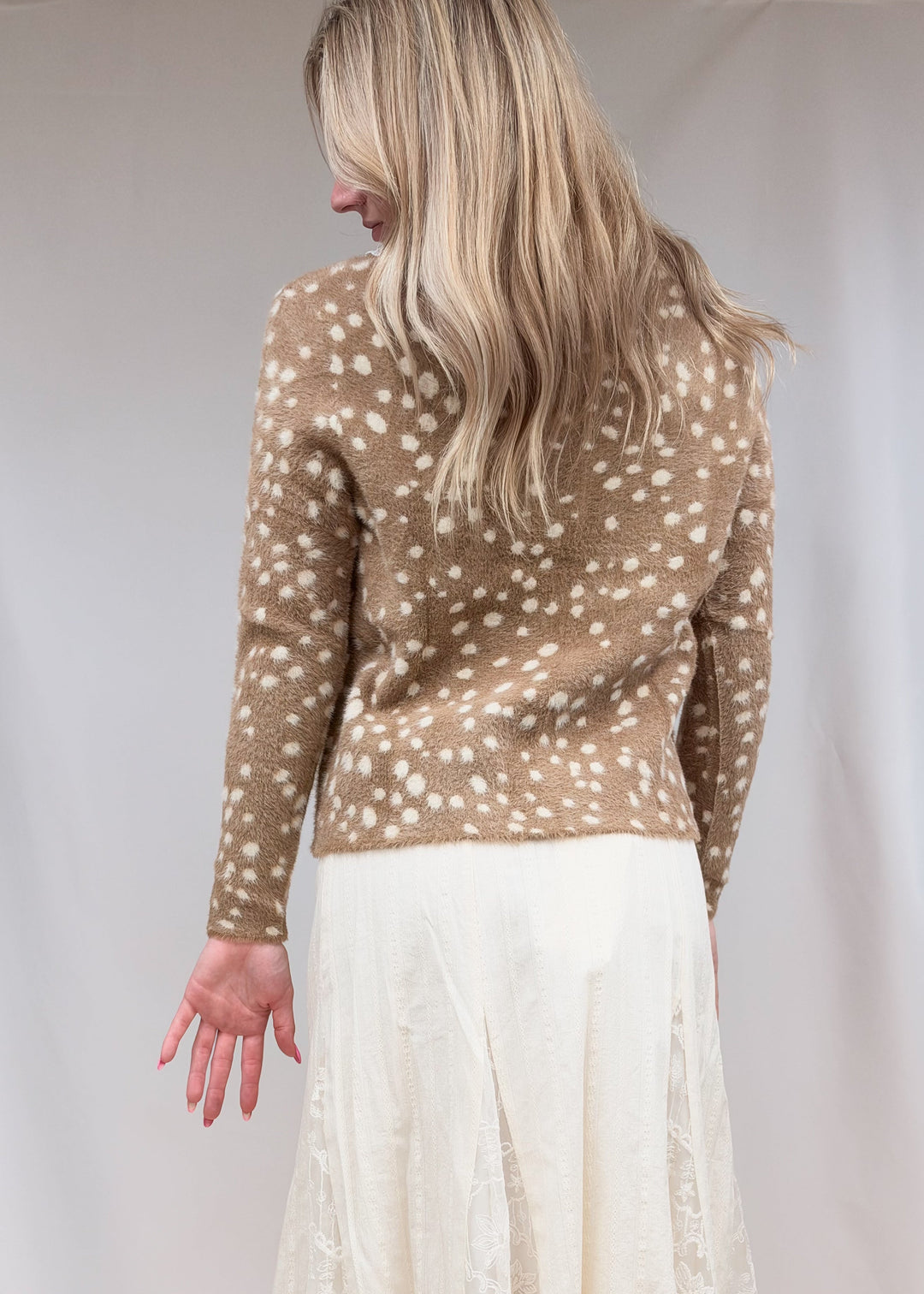 Woman shown from back view wearing fawn print fuzzy cardigan and lace detail maxi skirt on plain background