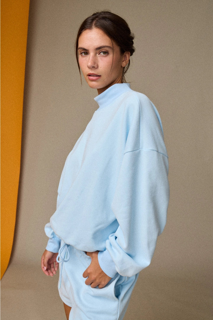 Woman wearing a light blue tracksuit against a neutral background