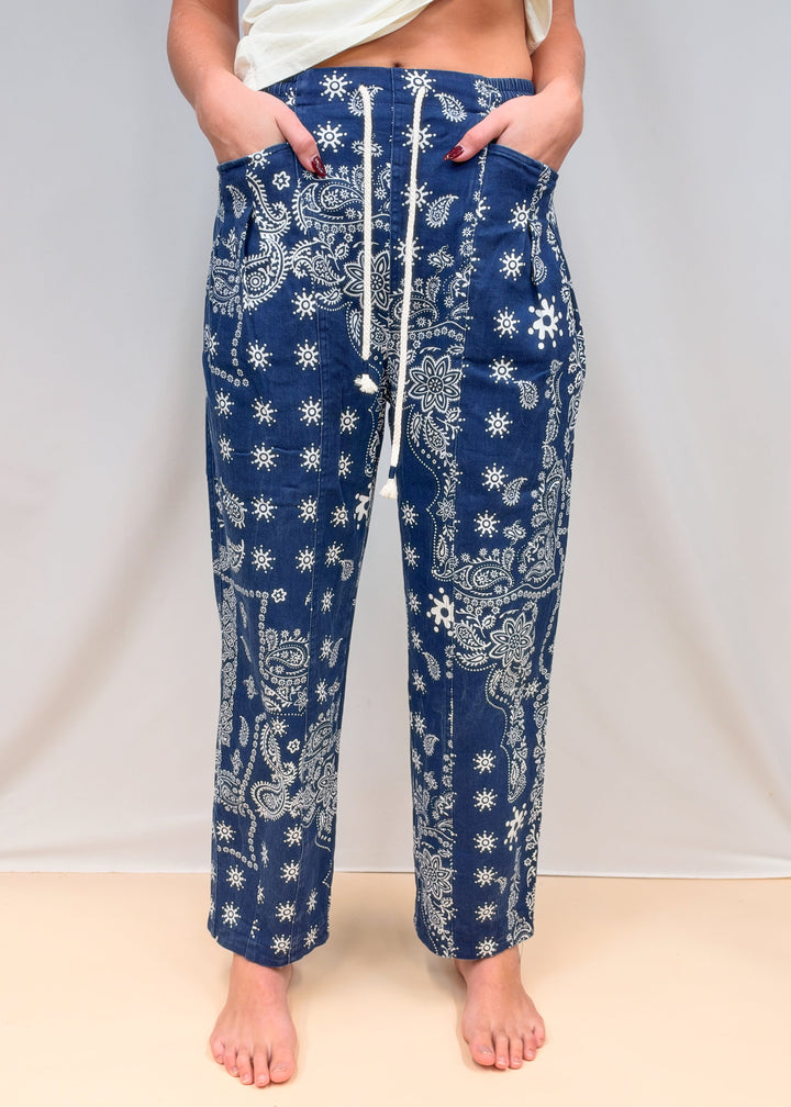 Woman shown waist down wearing blue paisley pull on pants on plain background