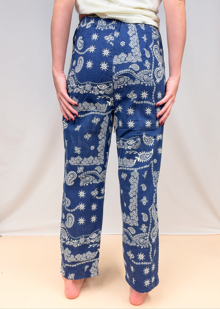 Woman shown from back view waist down wearing blue paisley pull on pants on plain background