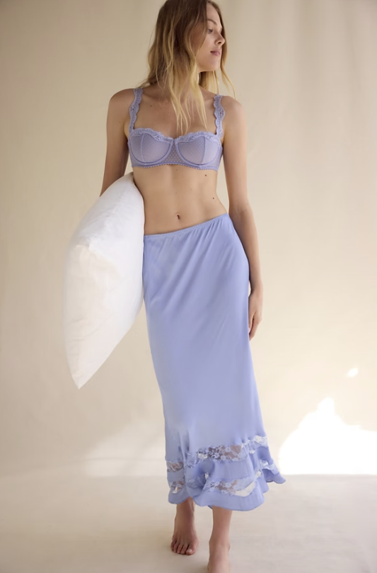 Woman wearing a light purple bikini with a matching sarong against a neutral background