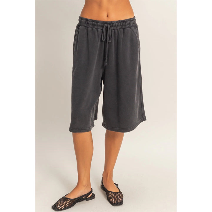 Person wearing dark gray shorts on a plain background