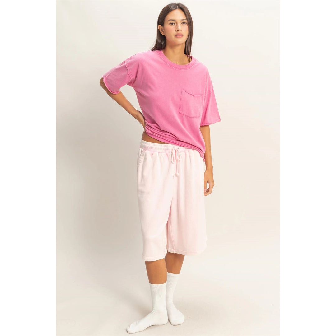Woman wearing a pink oversized t-shirt and light pink pants on a white background