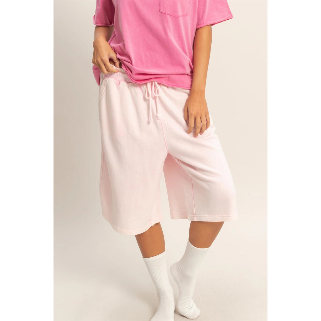 Person wearing a pink top and light pink drawstring pants on a plain background