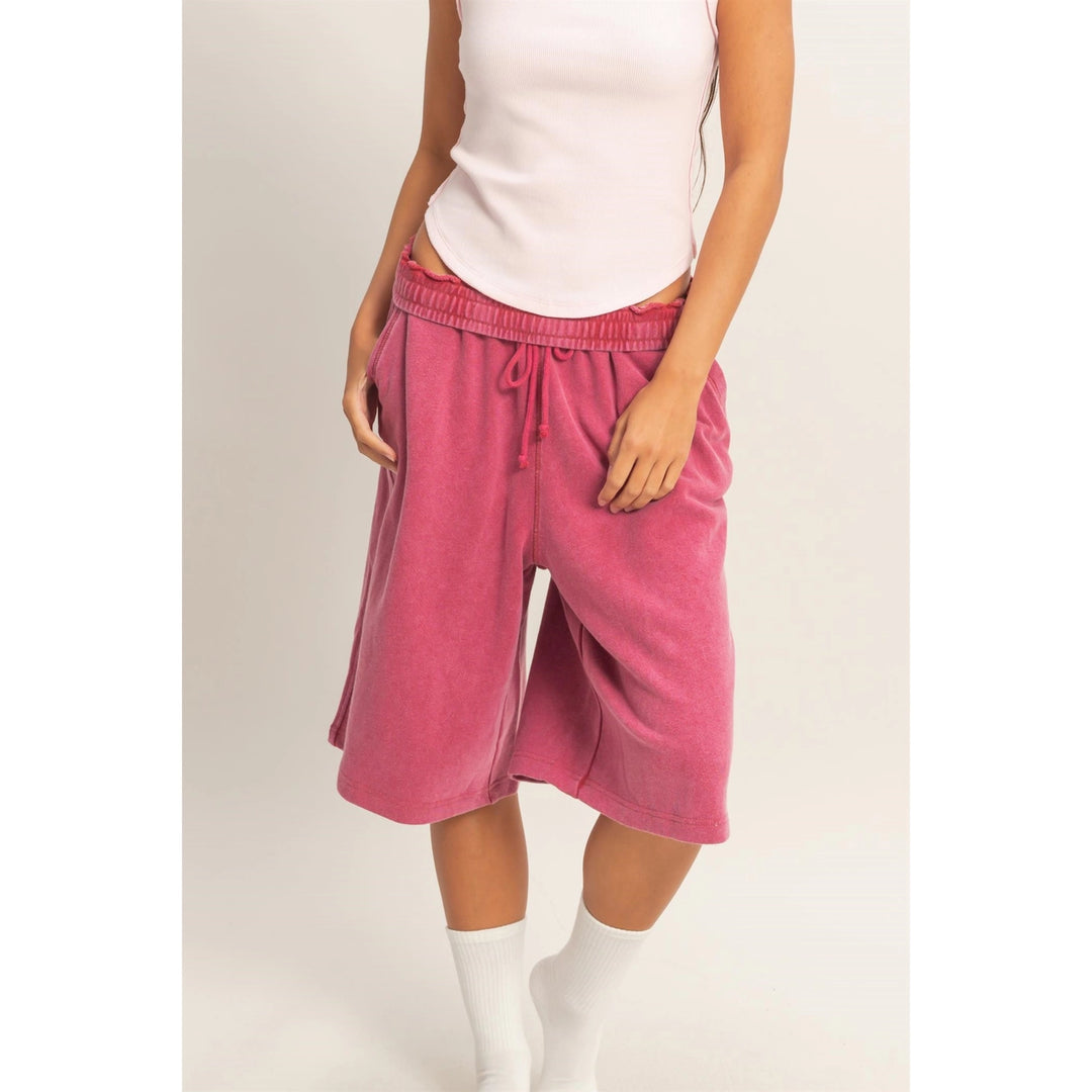 Person wearing pink shorts and a white top on a plain background