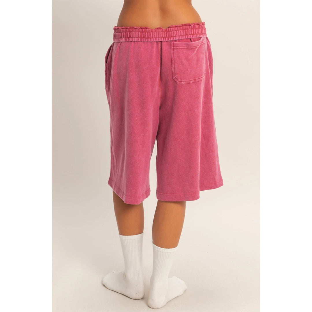 Pink shorts worn by a person on a plain background