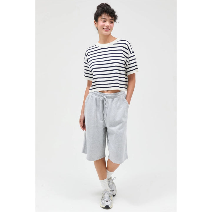Person wearing a striped shirt and gray shorts on a white background