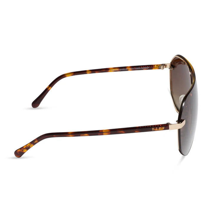 A pair of DIFF sunglasses with a classic aviator design, featuring a brown and amber tortoiseshell acetate frame and dark brown lenses, shown from a side profile view on a white background.