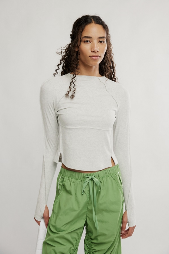 woman wearing white long sleeve top and green pants on white background