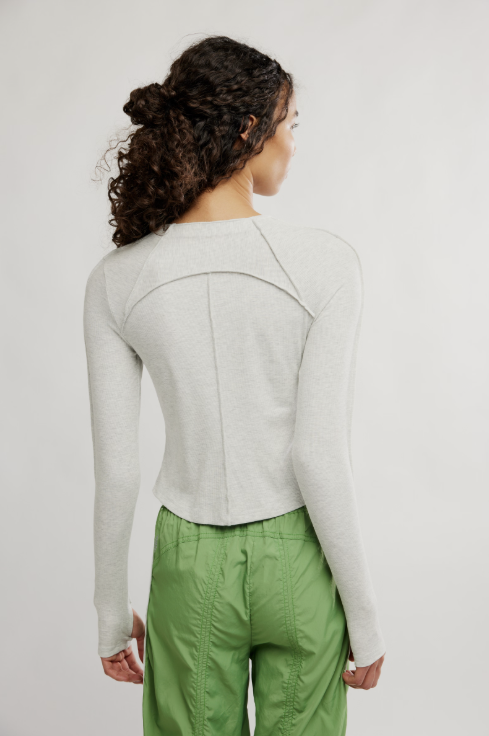 Person wearing a light gray shirt and green pants on a white background