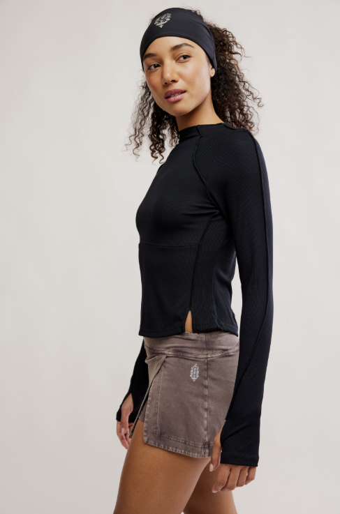 Woman wearing a black long-sleeve top and brown shorts on a white background