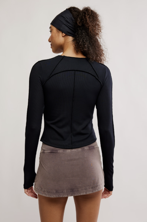 Person wearing a black long-sleeve top and gray skirt on a plain background