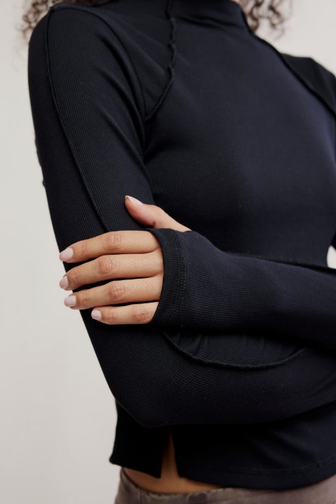 Person wearing a black long-sleeve top with a blurred background
