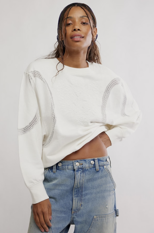 Woman wearing white sweatshirt with lace detail and jeans on white background