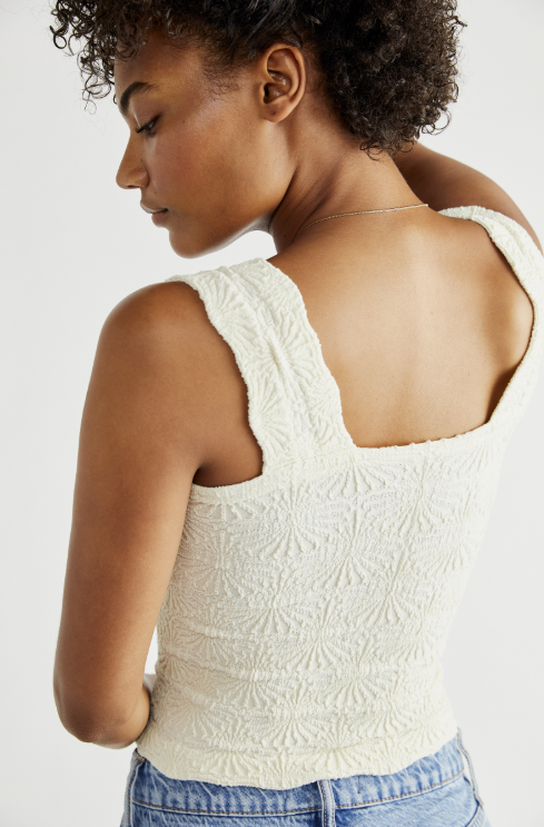 Woman wearing a textured white sleeveless top with a plain background