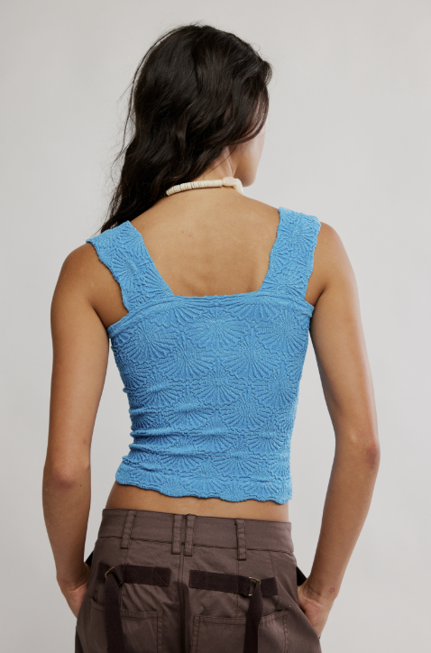 Woman wearing a blue sleeveless top against a plain background