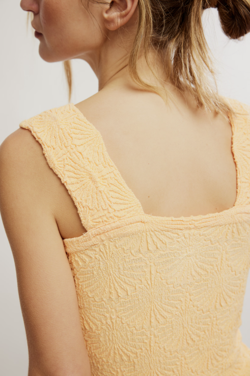 Yellow textured sleeveless top worn by a person on a light background