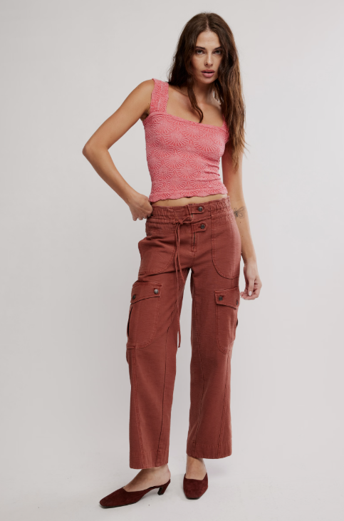 Woman wearing a pink top and brown cargo pants on a white background