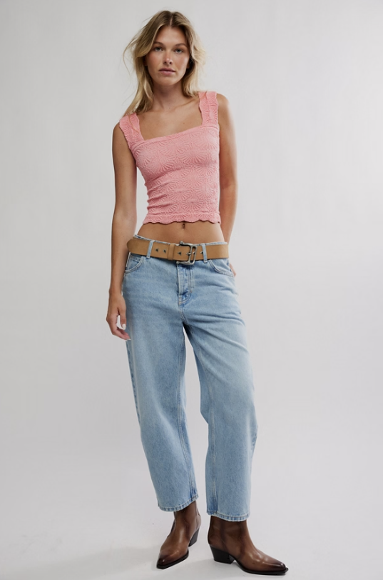 Woman wearing a pink top and light blue jeans on a plain background
