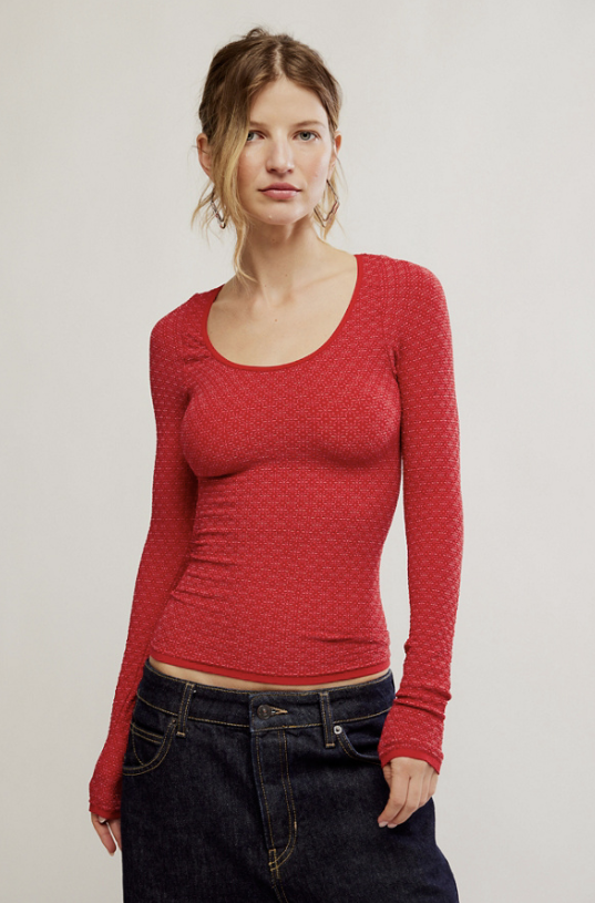 Woman wearing long sleeve red top with dark denim jeans on white background