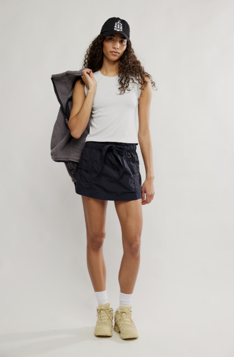 Woman wearing grey tee and black skirt on white background