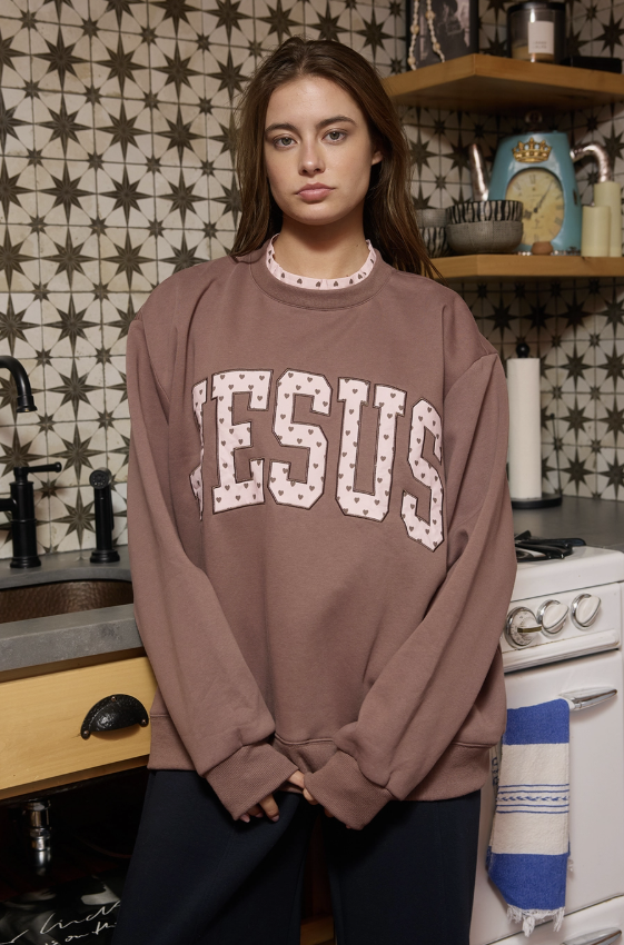 A woman wearing a brown sweatshirt with &