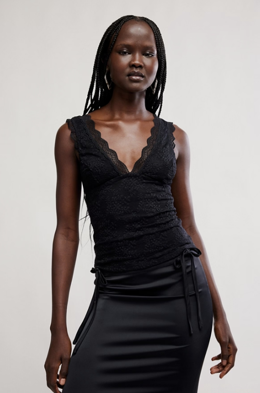 Woman wearing a black lace top and skirt set against a plain background
