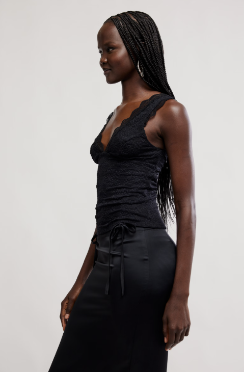 Woman wearing a black sleeveless top and black pants on a light gray background