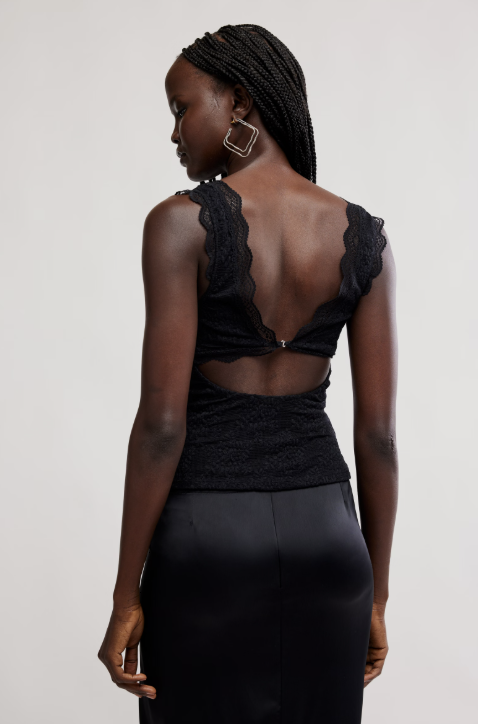 Woman wearing a black dress with a unique back design on a plain background