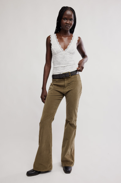 Woman wearing a white top and brown pants on a plain background