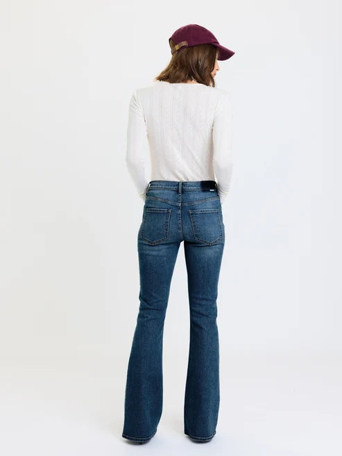 Back of woman wearing dark blue jeans and white top on white background