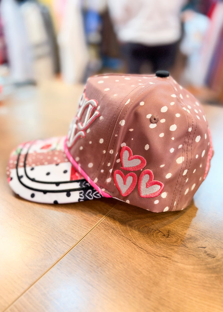 Brown polka dot trucker hat shown from side view with embroidered hearts 