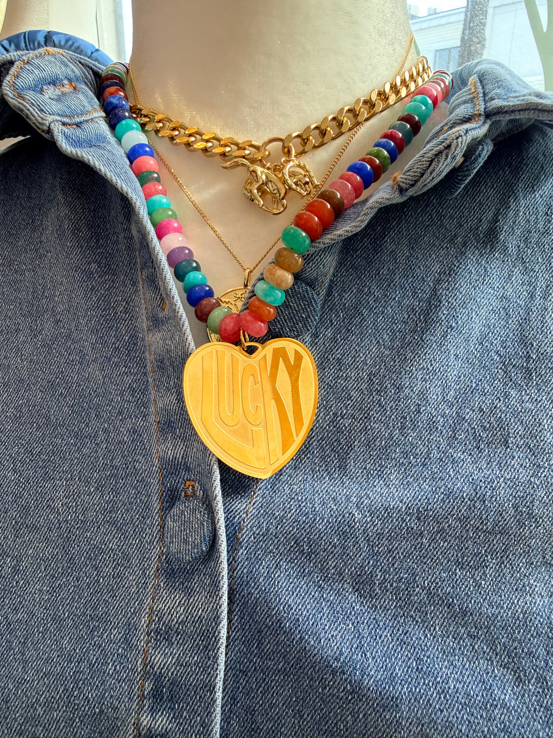 Colorful beaded bracelet with a gold heart charm on a denim surface