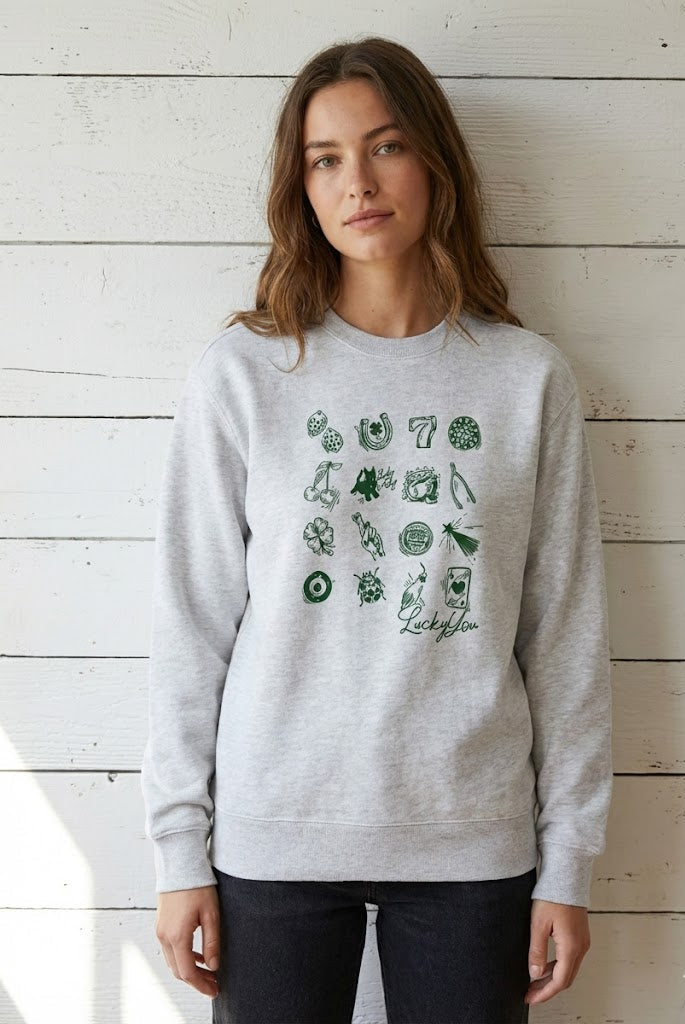 Woman wearing a gray sweatshirt with green graphics against a wooden wall.
