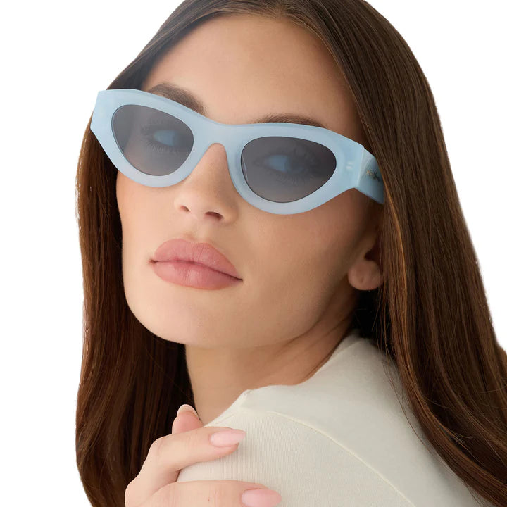 Woman wearing pastel blue sunglasses on white background