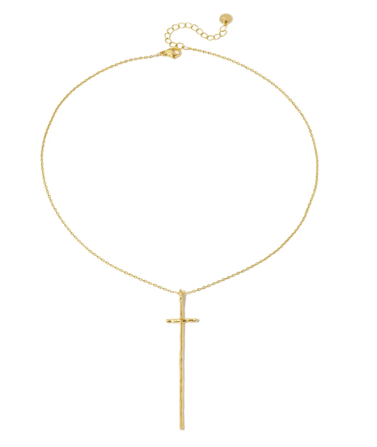 A delicate gold chain necklace featuring a long, minimalist vertical cross pendant, displayed against a solid white background.