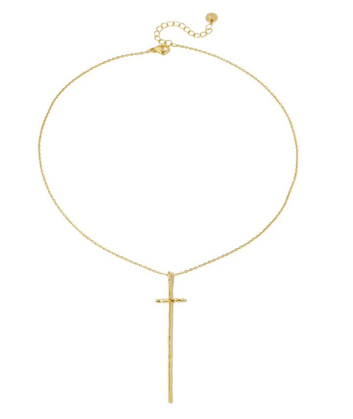 A delicate gold chain necklace featuring a long, minimalist vertical cross pendant, displayed against a solid white background.
