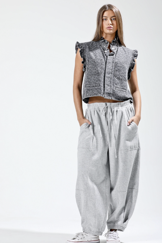 Woman wearing a sleeveless denim top and gray wide-leg pants on a white background