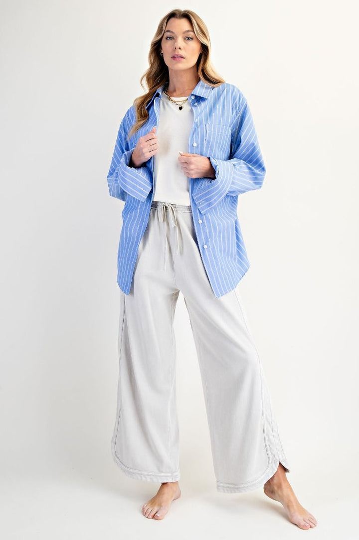 Woman wearing a blue striped shirt and white pants on a white background